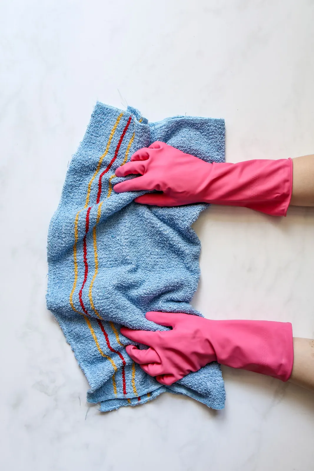 Gloved hand wiping a stone surface with a cloth.